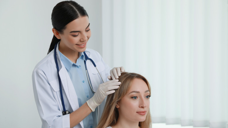 A trichologist examines a patient