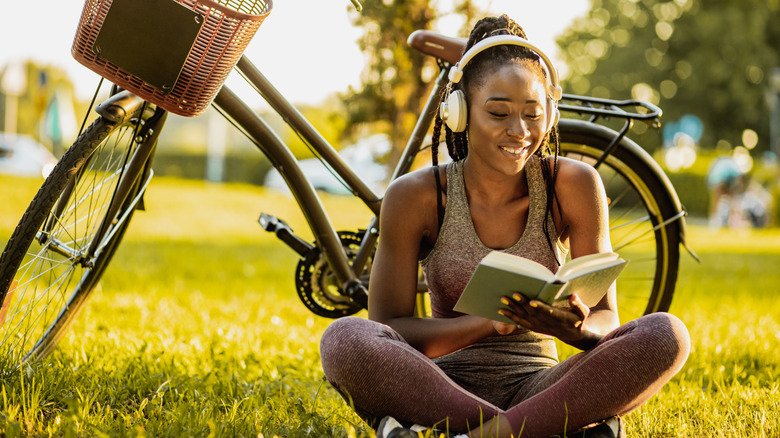 Woman with headphones and bike reading outside