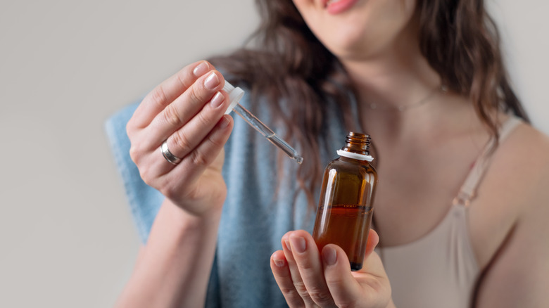 A woman holding a brown bottle of serum