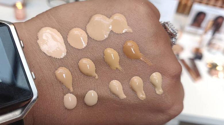Hand with 13 different foundation swatches