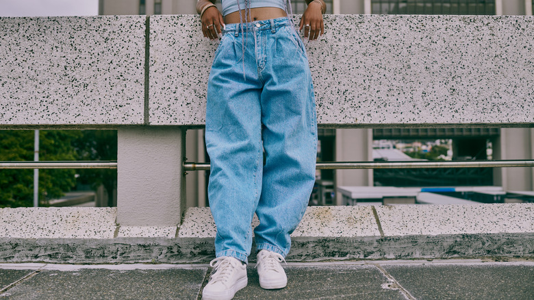 Woman standing in white chunky sneakers and loose fitting jeans