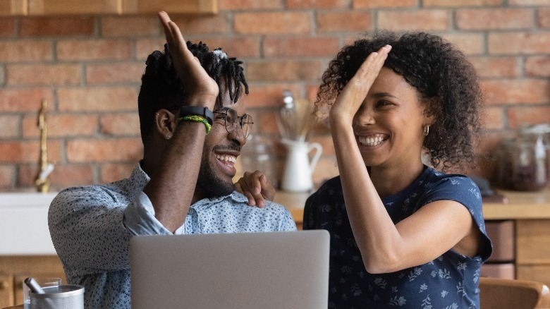 Couple high-fiving by laptop