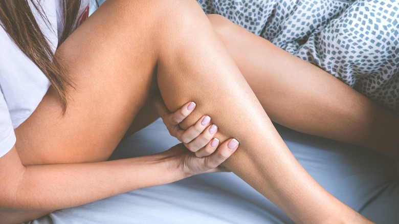 woman clutching painful leg 
