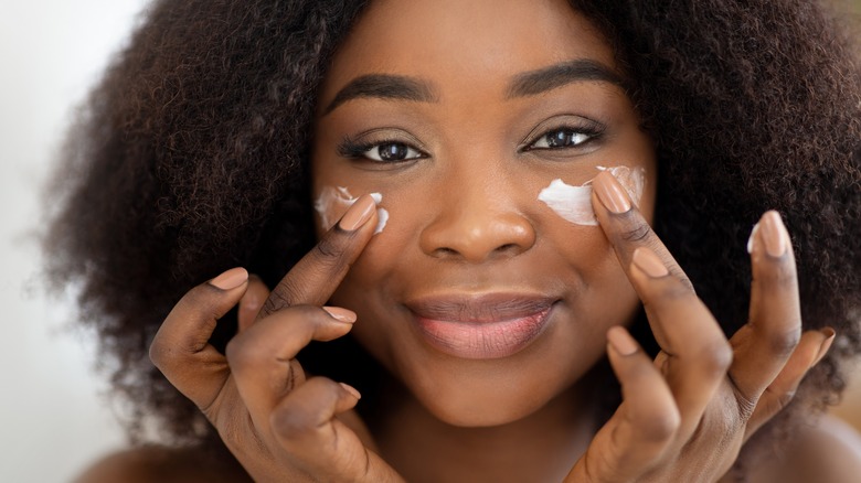 Woman applying facial moisturizer