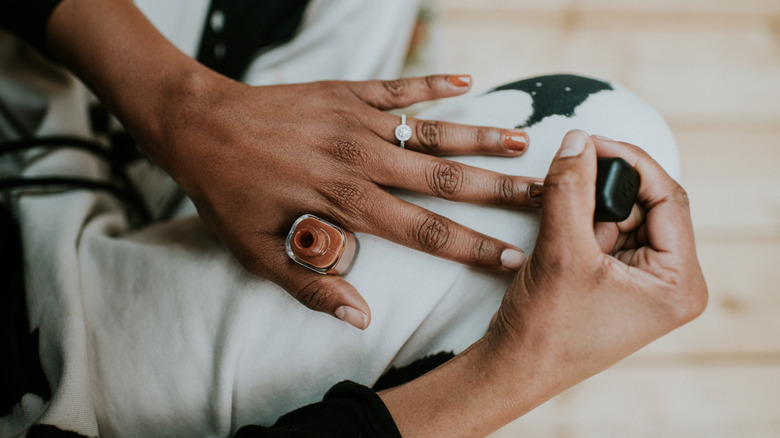 A person is applying nail polish on their finger nails