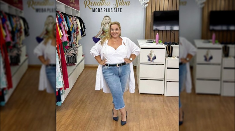 A woman wearing denim capris with a white corset top and a long white shirt