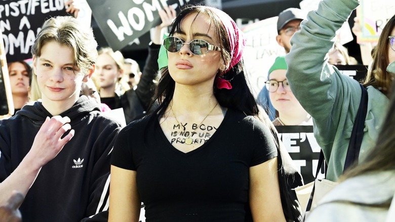 Woman in a march with writing on her collarbone