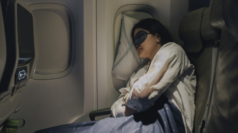Woman sleeping with sleep mask on airplane