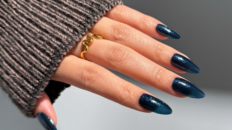 Close up of a hand with sparkly, navy blue nail polish