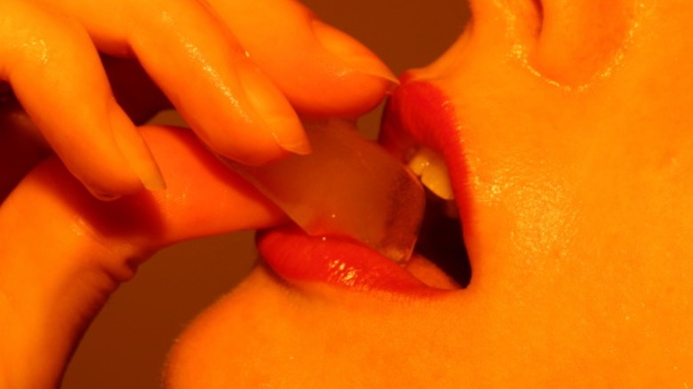 A person putting an ice cube in their mouth