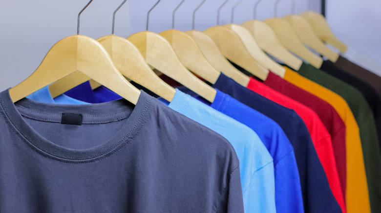 Rack of colorful t-shirts on wooden hangers
