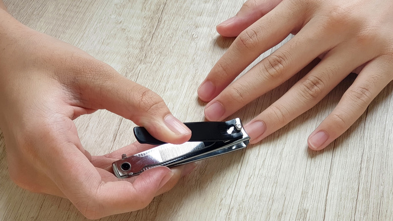 A person using nail clippers on finger nails