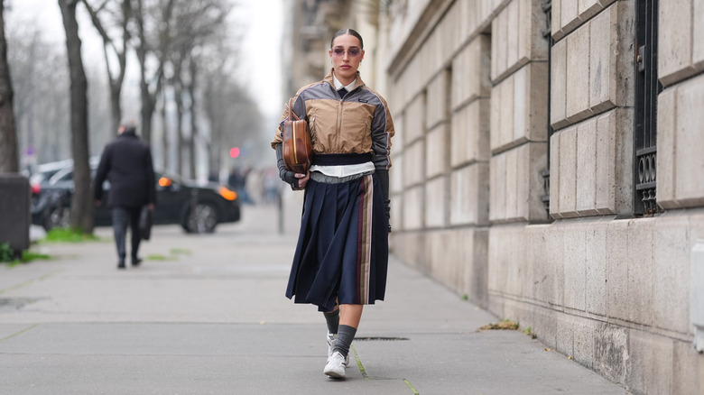 Woman wearing a midi skirt and sneakers at Paris fashion week