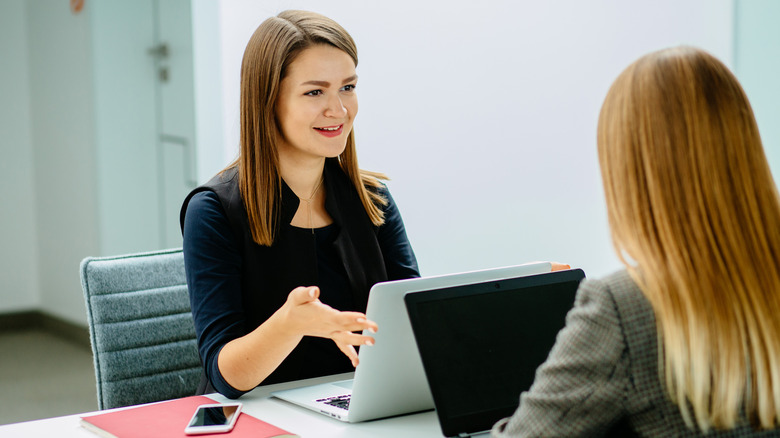 two women seated behind laptops