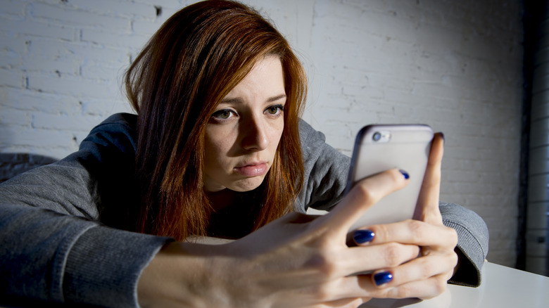 A woman staring sadly at her phone