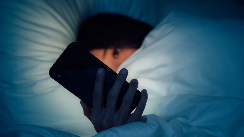 A woman waking up yawning with a sleep mask on her head
