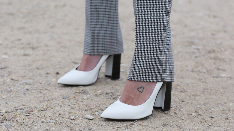 tattoo of a heart on a foot wearing white high heels