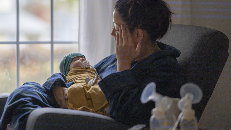 Woman holds infant exhausted