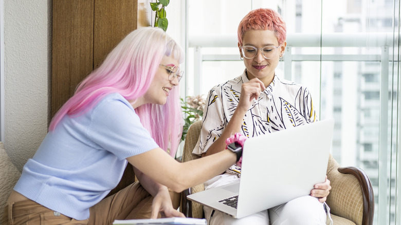 Two woman look over laptop