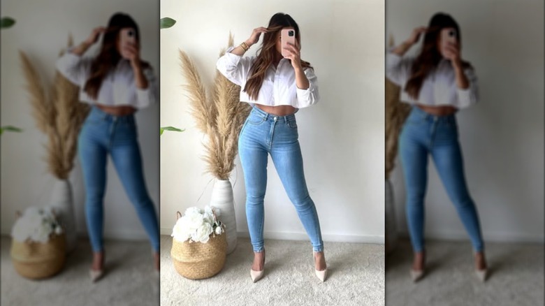 A woman taking a photo of herself in the mirror and wearing skinny jeans