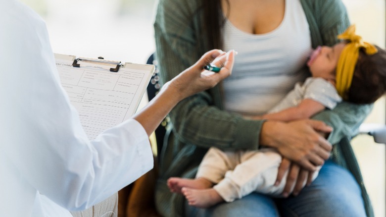Woman holding baby with doctor