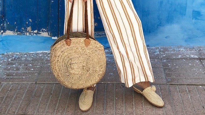 A woman wearing raffia shoes with a raffia bag