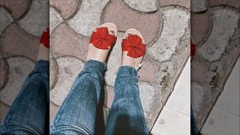 Woman wearing flat slides with red bow