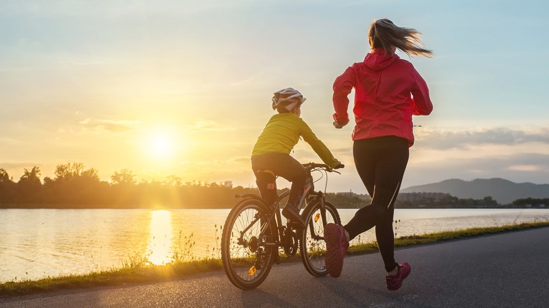 Woman running alongside a child on a bike