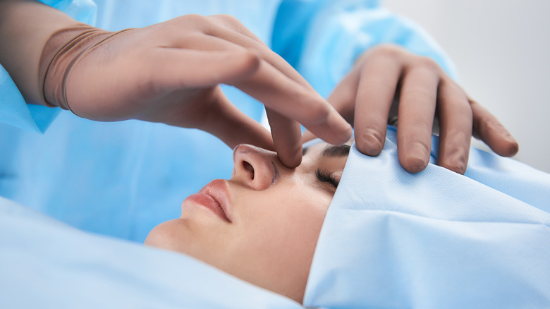 Surgeon touching woman's nose