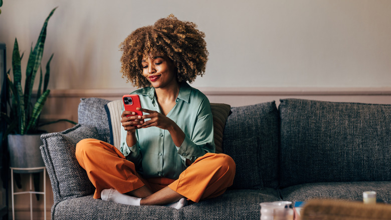 Woman sitting on couch holding phone