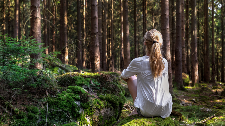 Woman sitting barefoot in forest
