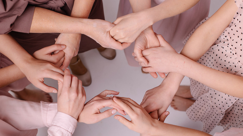 four women holding hands 