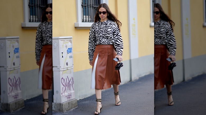 A woman with a zebra print blouse and a brown skirt